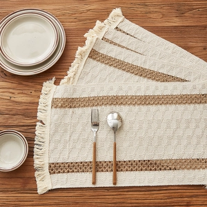 Boho woven table runner with tassels and brown stripes on a rustic wood dining table