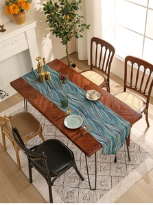 Deep blue abstract wave table runner with elegant tassels on a dark wood dining table