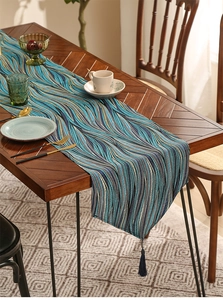 Close-up of luxury wavy table runner with blue abstract patterns and decorative tassels