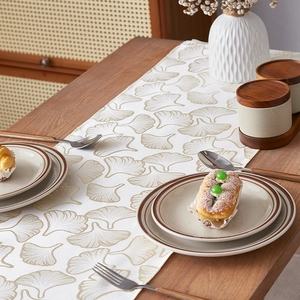 Luxury ginkgo leaf table runner in light brown and white on a wooden dining table