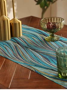Detail of luxury blue and gold wavy jacquard table runner on a dark wood grain texture surface