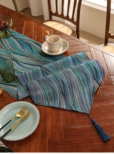 Close-up of blue wave pattern jacquard table runner with decorative tassel on wood table
