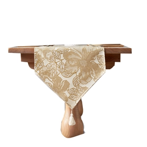 Luxurious beige gold floral jacquard table runner with cotton tassel on dark wood surface