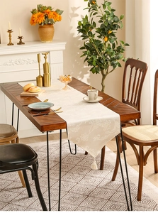 Detailopname van de crème jacquard tafelloper met bloemmotief en decoratieve kwastjes