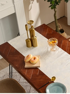 Detail van de ivoren damast tafelloper met bloemmotieven op een houten tafel in luxe stijl