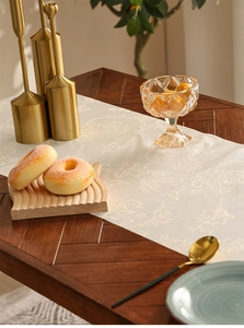 Detail van de jacquardtextuur van de dagbloem op een luxe beige tafelloper met kwasten