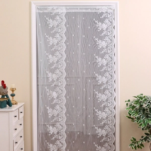 White floral lace curtain with wavy edges hanging in a warm and cozy home interior