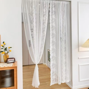 White French lace curtain with floral patterns and wavy edges in a cozy home setting
