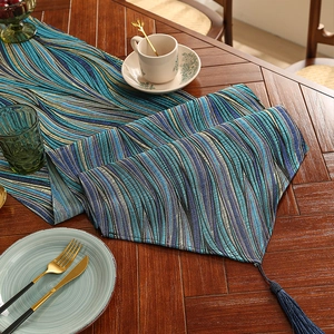 Modern wavy table runner in blue tones with elegant tassel detail on wood table