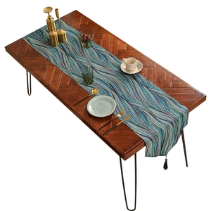 Luxurious wavy table runner in blue and yellow with black tassels on a wooden dining table