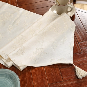 Elegante ivoren jacquard tafelloper met zijdeglans en afwerking met kwastjes