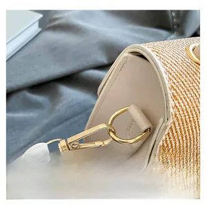 Close-up of golden hardware clasp and woven texture on a contrast leather crossbody bag