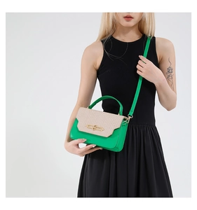 Detail of green leather handbag with straw woven flap and golden metal clasp closure