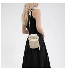 Detail of woven straw phone bag with white leather trim on a black dress model