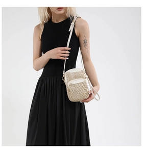 Detail of straw woven crossbody bag with dual zippers and white leather strap