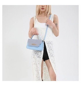Detail of blue and grey patchwork crossbody bag with elegant gold twist-lock fastener