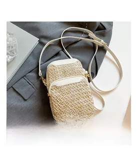 Detail of woven straw mini crossbody bag with white trim on a grey blazer backdrop