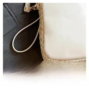 Detail of white leather and straw woven crossbody bag with gold hardware and wide strap