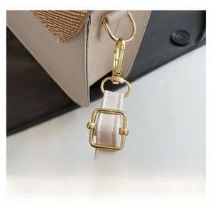 Detail of adjustable strap with gold-tone metal hook on beige patchwork crossbody bag