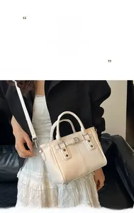 Detail view of white lychee leather tote bag with buckle straps and metallic stud accents