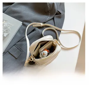 Internal capacity of cream white leather mini square bag showing phone and lipstick