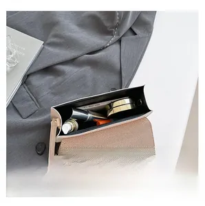 Detail view of the interior compartment holding makeup and a phone in a cream crossbody bag