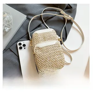 Macro detail of straw-woven phone bag featuring white leather trim and gold hardware