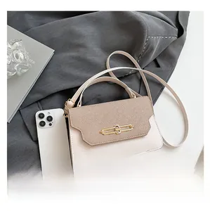 Detail view of cream crossbody bag featuring textured flap and gold metal bar buckle