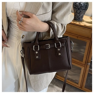 Detail of dark brown lychee leather texture and silver hardware on motorcycle tote bag