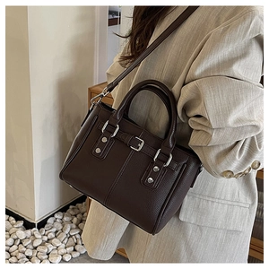 Detail of dark brown pebble leather tote bag with silver rivets and buckle straps