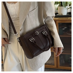 Detail of dark brown lychee grain leather tote bag with silver buckles shown on model