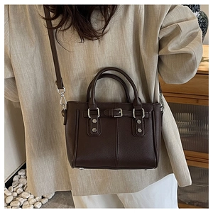 Close-up of deep brown lychee grain leather tote bag with silver hardware on a model