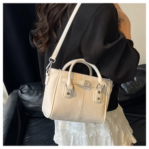Detail of off-white lychee leather tote bag featuring metal buckle straps and dual handles