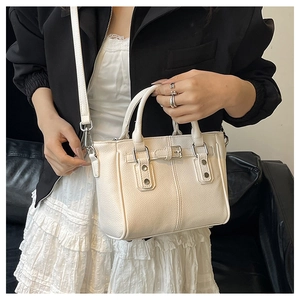 Detailed view of white pebble textured leather tote bag on model in minimal setting