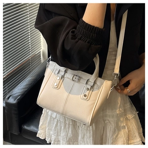 Fashionable creamy white grained leather tote bag styled on a chic black leather chair