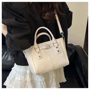 Detailed view of cream tote bag featuring textured leather and retro metal studs