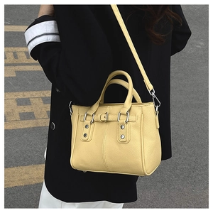 Close-up of yellow lychee leather handbag with silver hardware and studded buckle detail