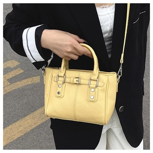 Close-up of yellow litchi pattern tote bag with metal buckles and detachable shoulder strap
