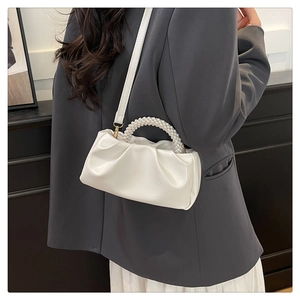 Detail of white pleated cloud bag featuring premium pearl handle and detachable leather strap