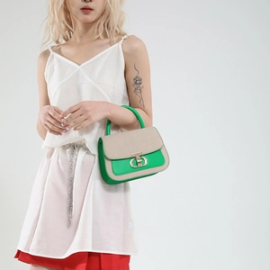 Chic green and beige contrast crossbody bag with gold D-buckle shown on a model