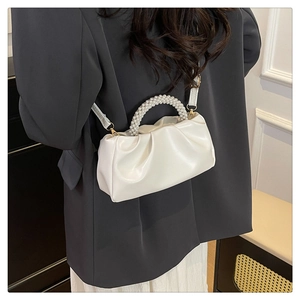 Détail du sac nuage plissé blanc avec poignée perle porté sur un blazer sombre