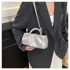 Silver metallic pleated cloud bag featuring elegant white pearl handle on a blazer