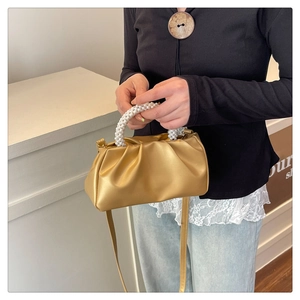 Détail du sac nuage plissé doré avec une poignée en perles et une longue bandoulière