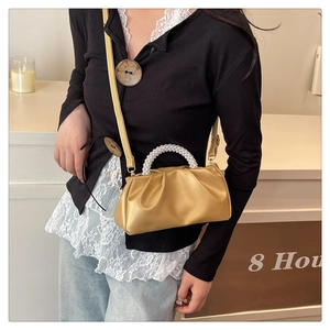 Close-up of champagne gold pleated cloud bag with elegant white pearl handle details