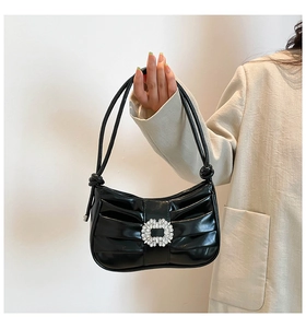 Detail of black pleated shoulder bag featuring a sparkling rhinestone buckle and thin straps