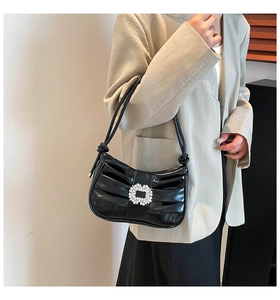 Close-up of elegant black pleated leather handbag with a luxury crystal buckle detail