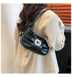 Detailed close-up of a black pleated shoulder bag featuring a sparkling crystal buckle detail
