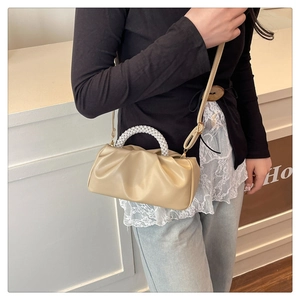 Detail of elegant beige cloud bag featuring pearl beaded handle and pleated PU leather finish