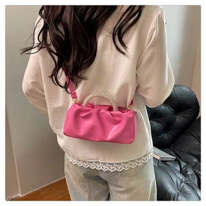 Close-up of pink pleated cloud bag with pearl handle and detachable shoulder strap