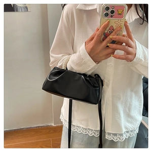 Detail of black pleated cloud bag with pearl handle and shoulder strap shown in a mirror
